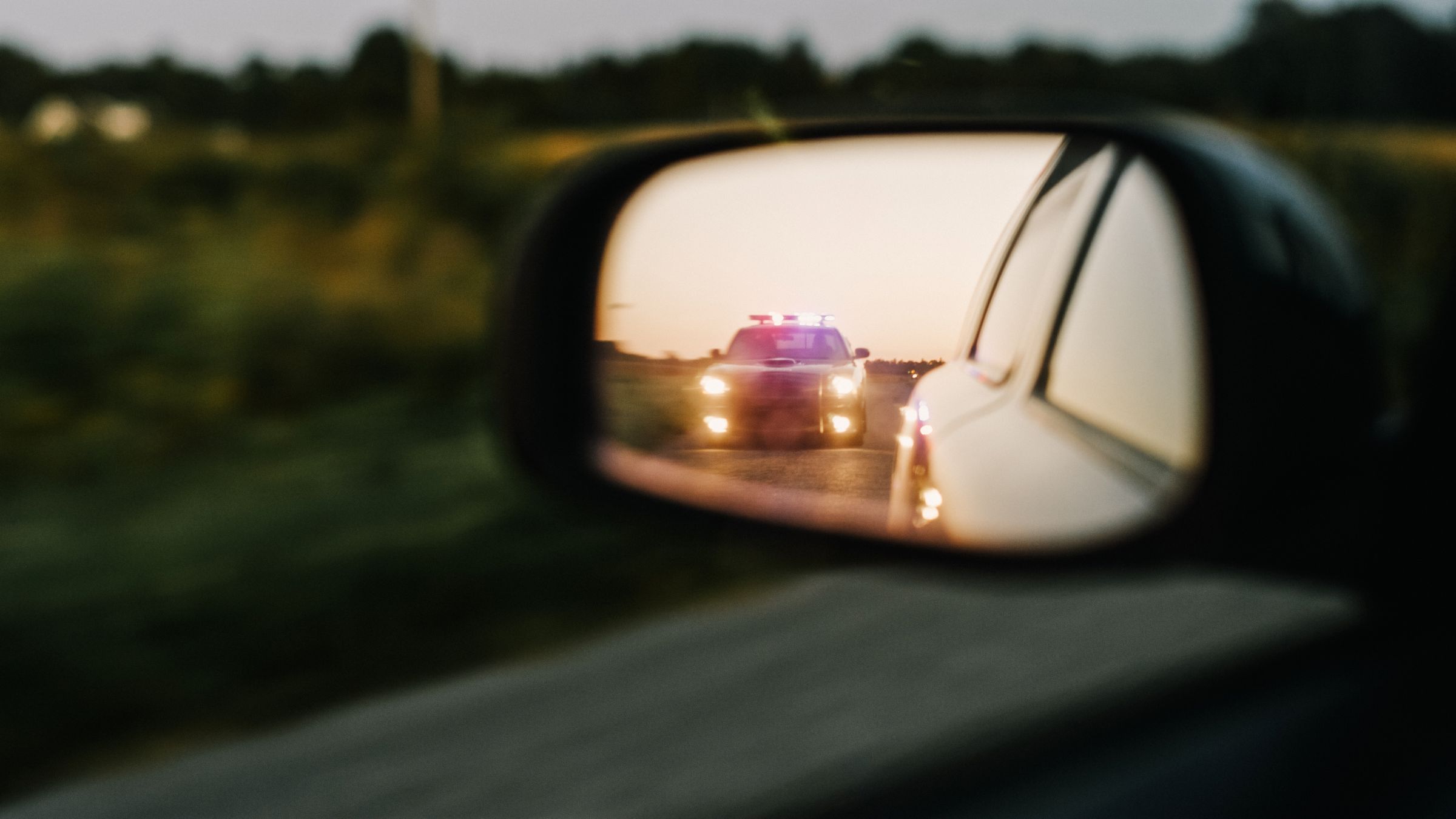 car mirror reflection showing police car with lights on